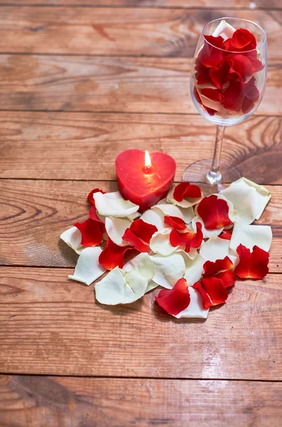 cam ahşap arka plan üzerinde kırmızı gül yaprakları ile kırmızı mum