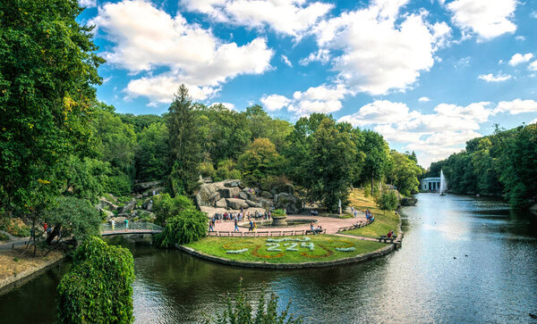 Uman, Cherkassy region, Ukraine - August 26, 2020: Lawns, flower beds, lakes and fountains of the famous Sofievsky arboretum and walking people, tourists in the city of Uman, Ukraine. Beautiful green garden in English style. Popular attraction