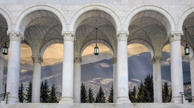 Güzel bir ortaçağ kemerli taş penceresi. Pencereden görkemli bir manzara. Kış dağları ve bir kale