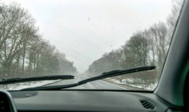 Araba silecekleri ön camı siliyor. Kar yağışı sırasında kış yolu