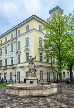  Lviv şehri, Ukrayna - 01 Mayıs 2019: Adonis 'in antik heykeli ve arka planda Lviv Belediye Binası ve eski tarihi Pazar Meydanı binasının ön cephesine karşı bir taş çeşme