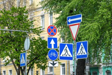 Şehir kavşağındaki yayaların, bisikletçilerin ve arabaların hareketlerini düzenleyen çeşitli tabelalar. Trafik yönetmelikleri ve yol güvenliği