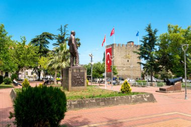 Trabzon, Türkiye - 14 Haziran 2021: Türkiye 'nin Trabzon kentindeki tarihi Atapark' ta Atatürk 'ün bronz heykeli, Mustafa Kemal. Antik bir Bizans kalesinin heybetli taş duvarları dalgalanan Türk bayrakları ve yeşil bir tropikal şehir parkı