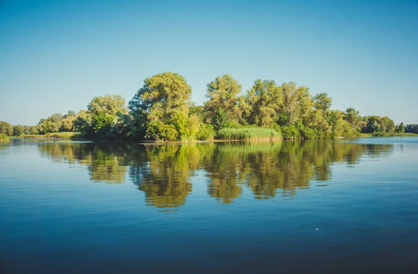 Fabulous reflection river island in serene surface of the water. Ukraine, the Dnieper river, vicinities of Kremenchuk