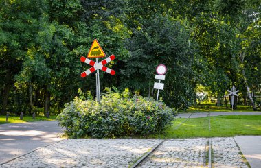 Şehir merkezi ve demiryolu taşımacılığı. Trafik kuralları ve kısıtlamalar, uyarı üçgeni yol işareti, demiryolu bariyerleriyle kesişiyor.