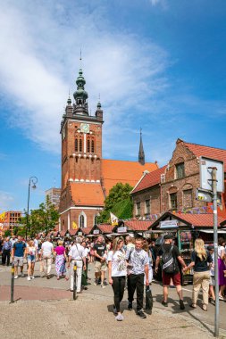 Gdansk, Polonya - 27 Temmuz 2025: Geleneksel St. Dominic Fuarı. Eski Gdansk Kasabası 'nda tatiller. Ortaçağ gotik caddesinde yürüyen ve kaldırım kafesinde yemek yiyen bir turist.