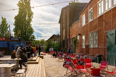 Gdansk, Polonya - 10 Mayıs 2025: Gdansk 'taki tarihi tersanenin ünlü turizm ve eğlence alanı. Yıkılan endüstri binaları, vinçler ve gıda alanlarından yiyecek alan insanlar.