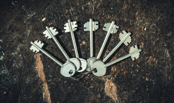 Набор старомодных ключей на фоне старого деревянного пня. Декор в деревенском стиле
