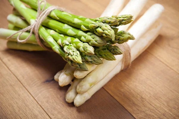 Bouquets d'asperges crues, vert et blanc, fond en bois — Photo