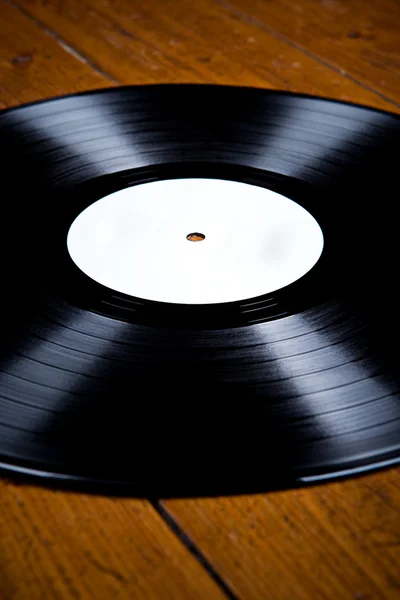 Vinyl record, lp, met witte etiket op een houten vloer, reflecties — Stockfoto