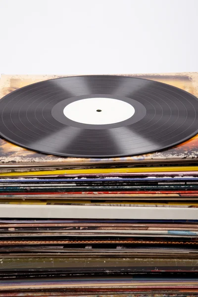 Schallplatte auf einem Turm aus unterschiedlich farbigen LP-Covern — Stockfoto