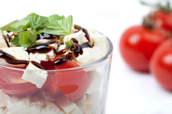 Gros plan de salade de tomates et fromage feta avec basilic dans un verre, fond blanc, isolé , — Photo