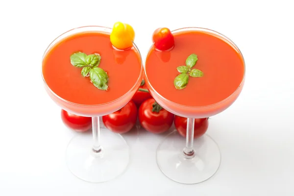 Due bicchieri da cocktail pieni di frullati al succo di pomodoro con pomodoro giallo e rosso su bicchiere, basilico verde in vetro, fondo bianco, isolato , — Foto Stock