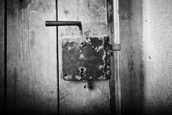 Rusty iron doorknob on old handmade wooden door, retro, black and white, vignette, textured — Stock Photo, Image