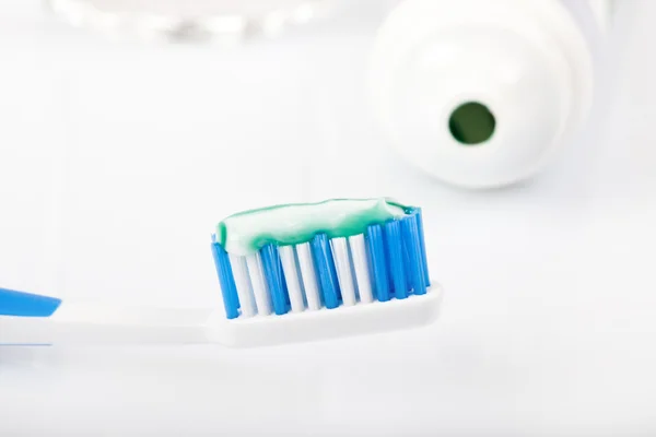 Dental care equipment, toothpaste on toothbrush, paste tube, glass of water, white background, — Stock Photo, Image