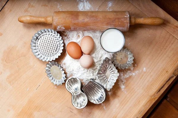 Ingredienti della pasta, latte, farina, uova, con mattarello in legno e taglierina retrò per biscotti natalizi — Foto Stock