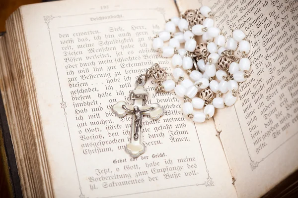 Rosary with jesus on crucifix on sides of opened bible, — Stock Photo, Image