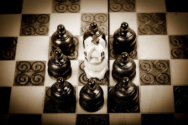 Chess King surrounded by group of opposing pawn, sepia, vintage — Stock Photo, Image