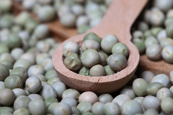 Green peas in wooden spoon, close up — Stock Photo, Image