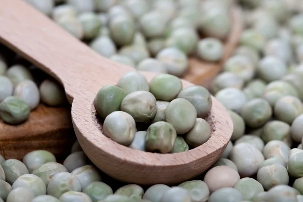 Wooden spoon with uncooked green peas — Stock Photo, Image