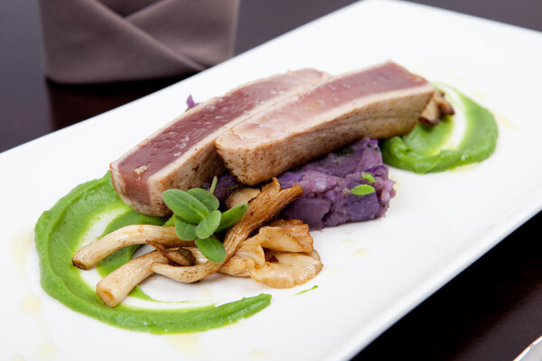 Seafood dinner with fillet of tuna, green pea puree, oyster mushrooms, and potatoes