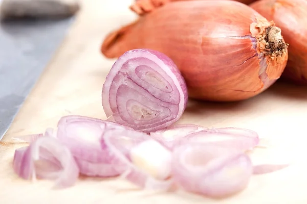 Shallot with sliced piece and old knife on wooden plate — Stock Photo, Image