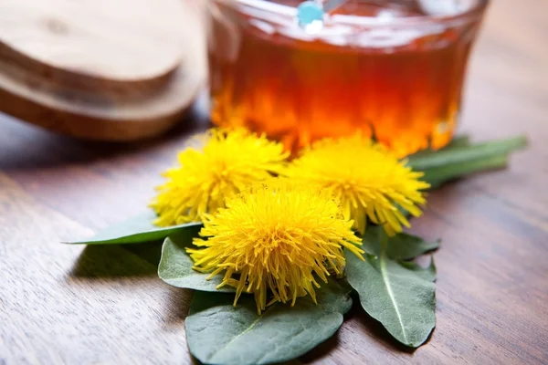 Paardebloem bloesem en blad met gouden honing op houten tafel — Stockfoto