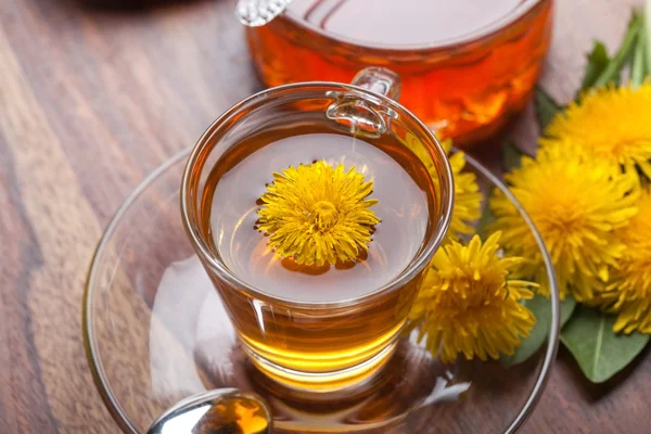 Herbal tea made of fresh dandelion essence, with honey, yellow blossoms and green leaf — Stock Photo, Image