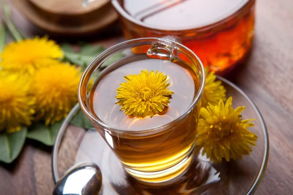 Dandelion herbal tea with yellow blossom in tea glass, with honey on wooden table — Stock Photo, Image