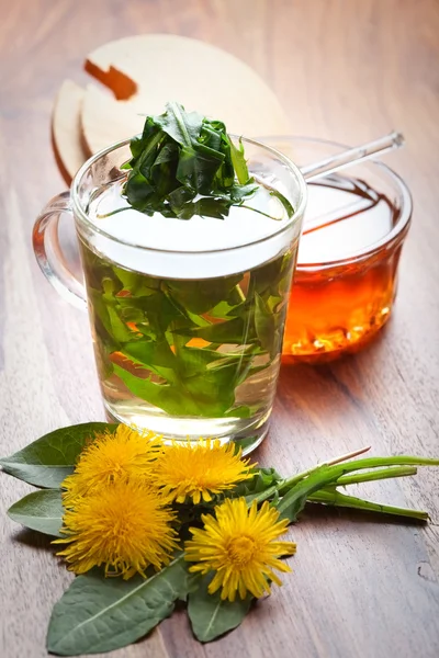 Paardebloem kruidenthee met vers blad in thee beker. op houten tafel — Stockfoto