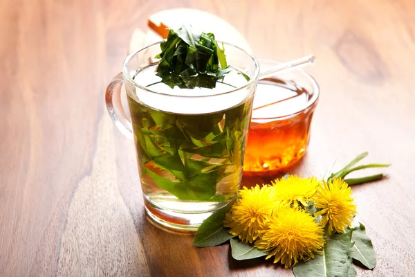 Tè alle erbe con tè al dente di leone in tazza di tè, miele e fiori gialli sul tavolo di legno — Foto Stock