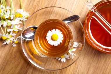 ahşap arka plan üzerinde çay fincanı içinde taze çiçeği ile bitkisel papatya çayı