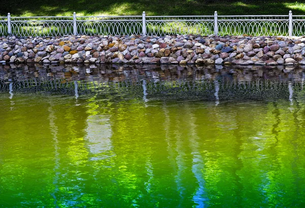 Horizontale levendige park hek in de buurt van groene vijver achtergrond — Stockfoto