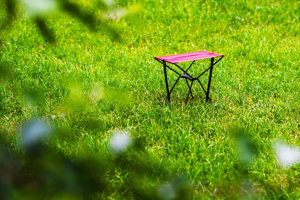 Poziomy żywe czerwone krzesło na Zielona trawa tło bokeh — Zdjęcie stockowe