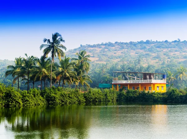 Horizontal vívido indiano casa palmas com rio reflexão backgr — Fotografia de Stock