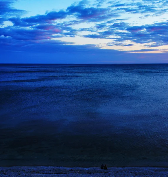 Пара встреч на фоне заката океана — стоковое фото