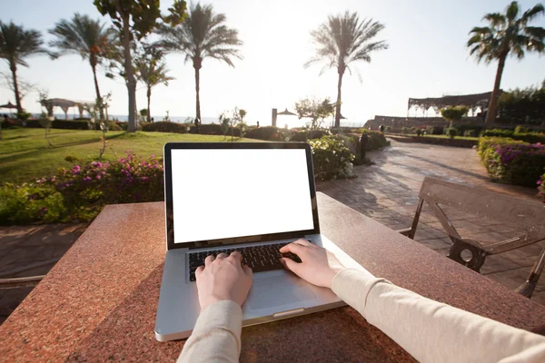 Businesswoman typing on her laptop with sunflare on the resort — Stock Photo, Image