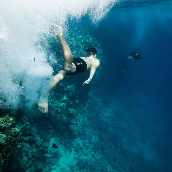 Tournage sous-marin d'un jeune homme sautant dans une mer rouge — Photo