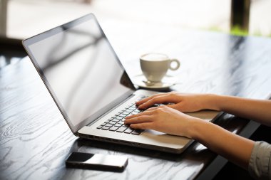 Kadın yanında tablet ile bir pencerenin önünde bilgisayarda çalışıyor