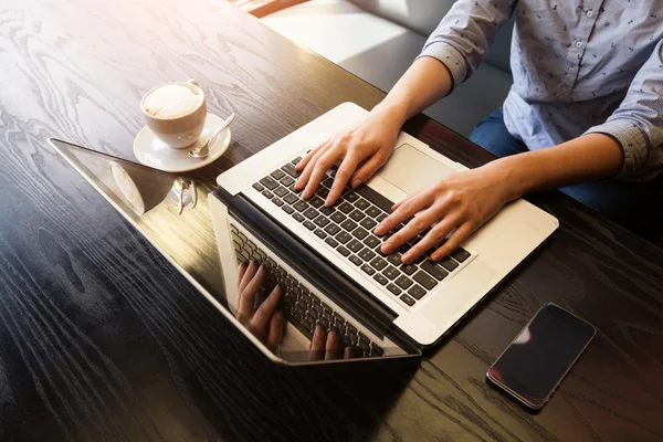 Femme travaille sur ordinateur devant une fenêtre avec tablette à côté de — Photo