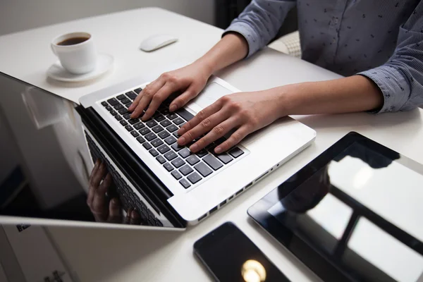 Vrouw die op laptop op houten balie in kantoor werkt — Stockfoto