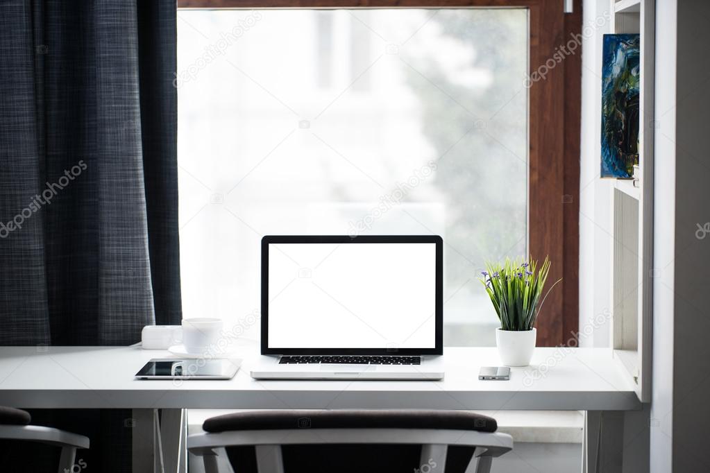 Office Desk Next To A Window With Laptop And Tablet Pc And A Sma