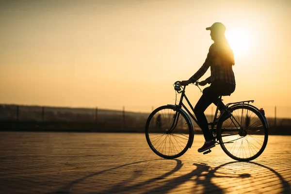 Vacker hipster flicka med cykel på vägen under solnedgången — Stockfoto