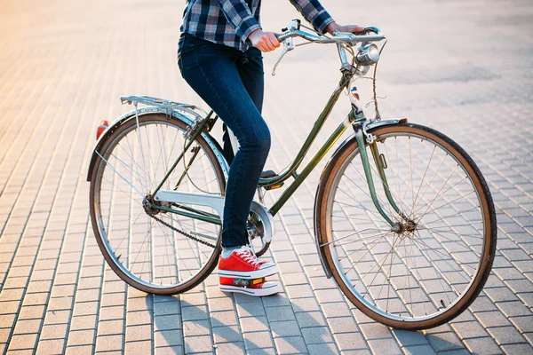 Beautiful hipster girl with a bicycle on the road during sunset — Stock Photo, Image