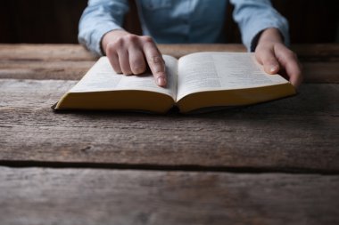 Karanlık bir İncil ile ahşap masa üzerinde dua eller kadın