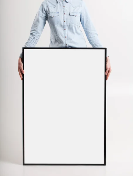 Mujer con cartel en blanco sobre fondo de pared —  Fotos de Stock