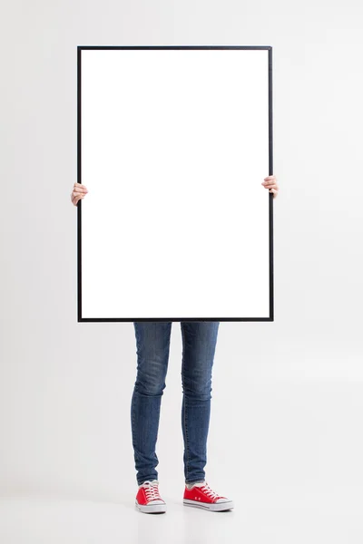 Mujer con cartel en blanco sobre fondo de pared —  Fotos de Stock