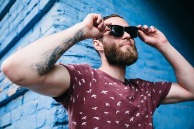 Mavi arka plan üzerinde güneş gözlüğü takıyor hipster çocuk