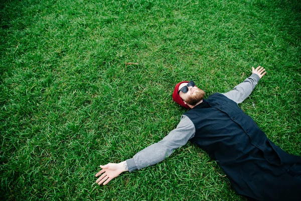 Hipster chico usando gafas de sol y acostado en la hierba — Foto de Stock