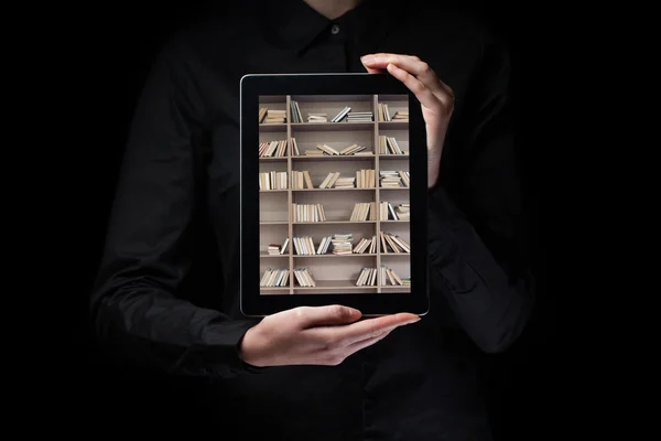 Handen houden en het tonen van een tablet pc met bibliotheek planken insi — Stockfoto